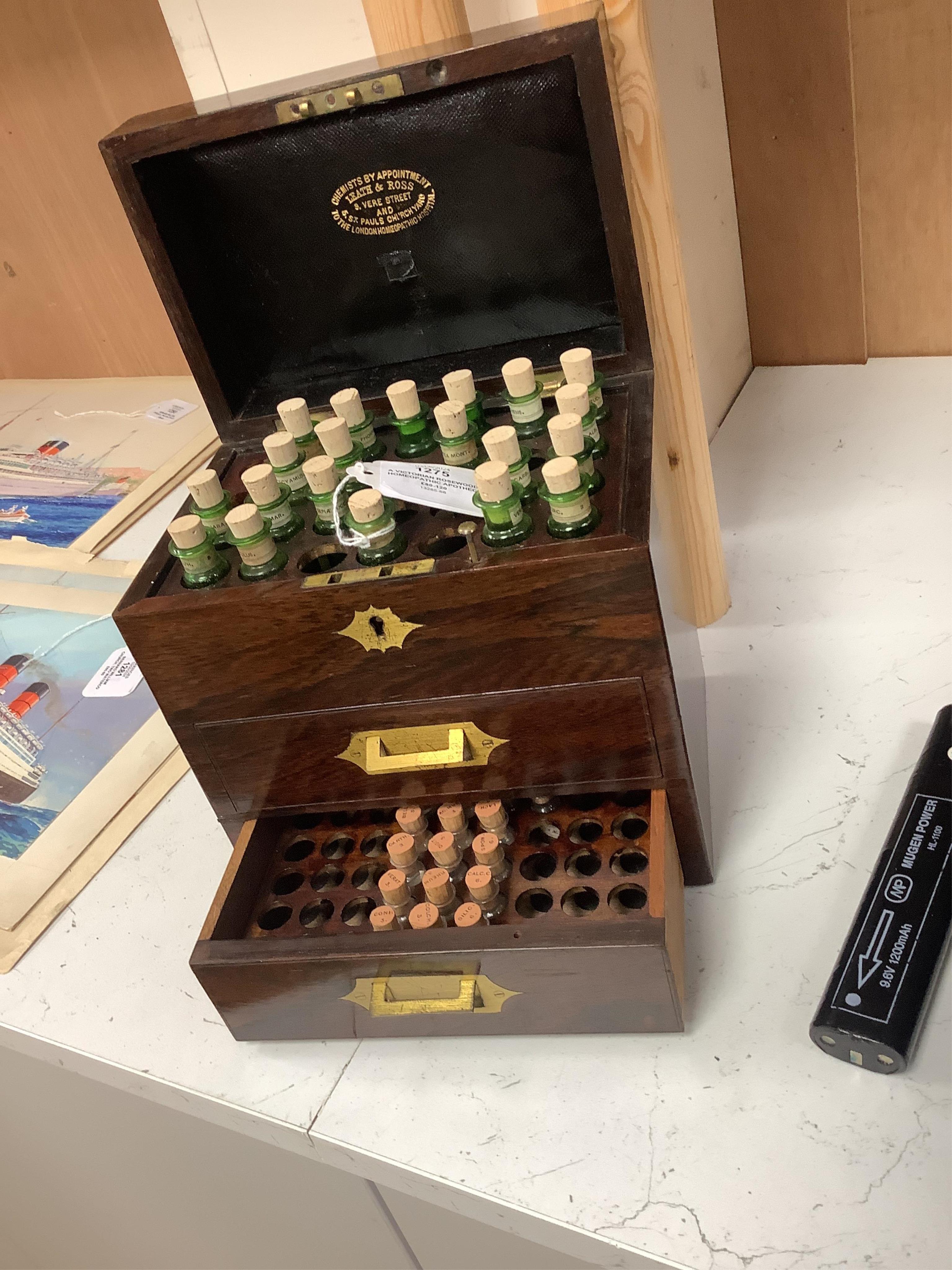 A Victorian rosewood homeopathic apothecary box, by Leath and Ross, two segmented drawers below a top opening section, containing a number of labelled chemists bottles, 21cm high, 20cm wide, 13.5cm deep